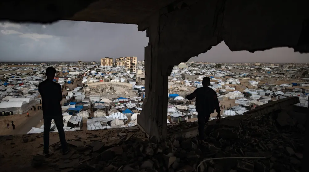 فلسطينيان يقفان داخل مبنى مدمر بسبب الحرب في خان يونس جنوب قطاع غزة (إ.ب.أ)