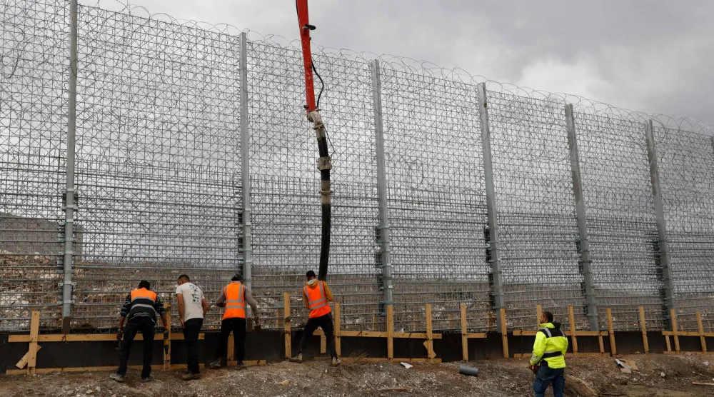 عمال إسرائيليون أثناء عملهم على السياج الإسرائيلي عند الحدود اللبنانية (أ.ف.ب)