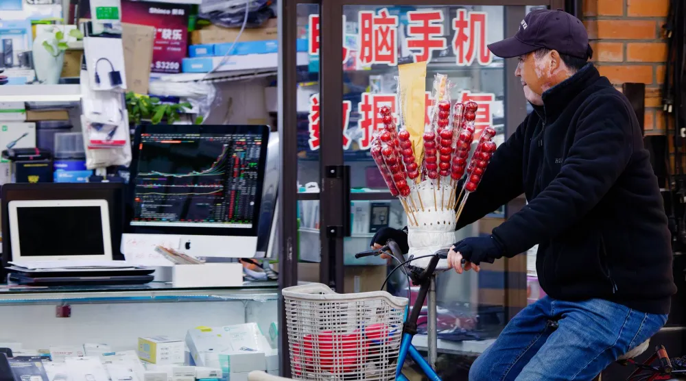 رجل يمر أمام متجر لبيع الإلكترونيات بمدينة شنغهاي الصينية (إ.ب.أ)