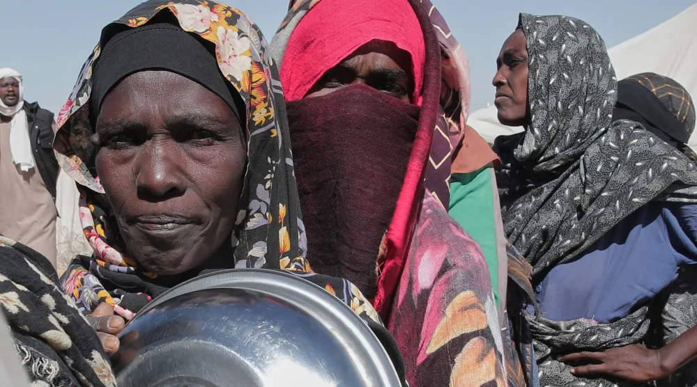 سودانيات ينتظرن الحصول على طعام في مخيم العفاض بالدبة شمال البلاد (أ.ب)