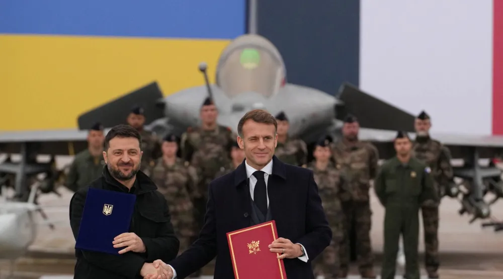 الرئيس الفرنسي إيمانويل ماكرون والرئيس الأوكراني فولوديمير زيلينسكي يتصافحان بعد توقيع اتفاقية في قاعدة فيلاكوبلاي الجوية بالقرب من باريس (رويترز)