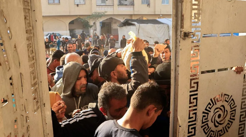 فلسطينيون ينتظرون لشراء الخبز من نقطة توزيع في خان يونس جنوب قطاع غزة يوم الاثنين (رويترز)