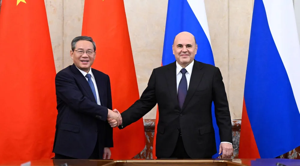 رئيس الوزراء الروسي ميخائيل ميشوستين (يمين) يصافح نظيره الصيني لي تشيانغ (إ.ب.أ)