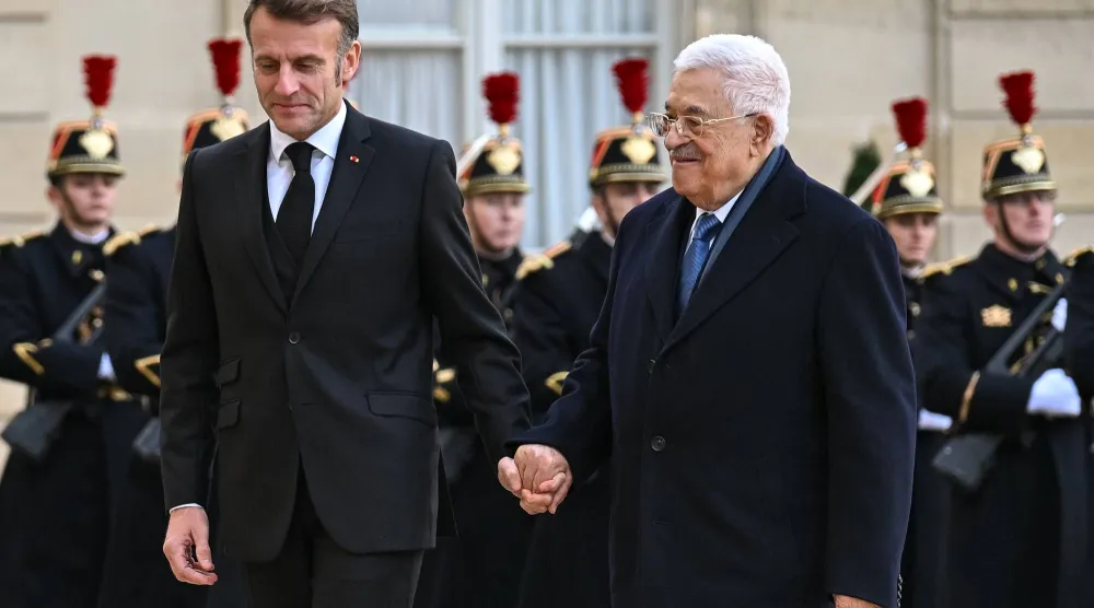الرئيس الفرنسي إيمانويل ماكرون يمسك بيد الرئيس الفلسطيني محمود عباس لدى وصوله إلى قصر الإليزيه يوم 11 نوفمبر 2025 (د.ب.أ)