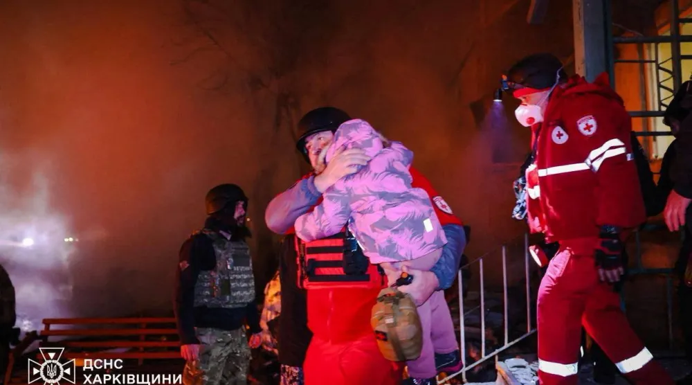 مسعف يحمل طفلاً أثناء إخلاء المبنى السكني الذي تضرر بغارة روسية على خاركيف (رويترز)