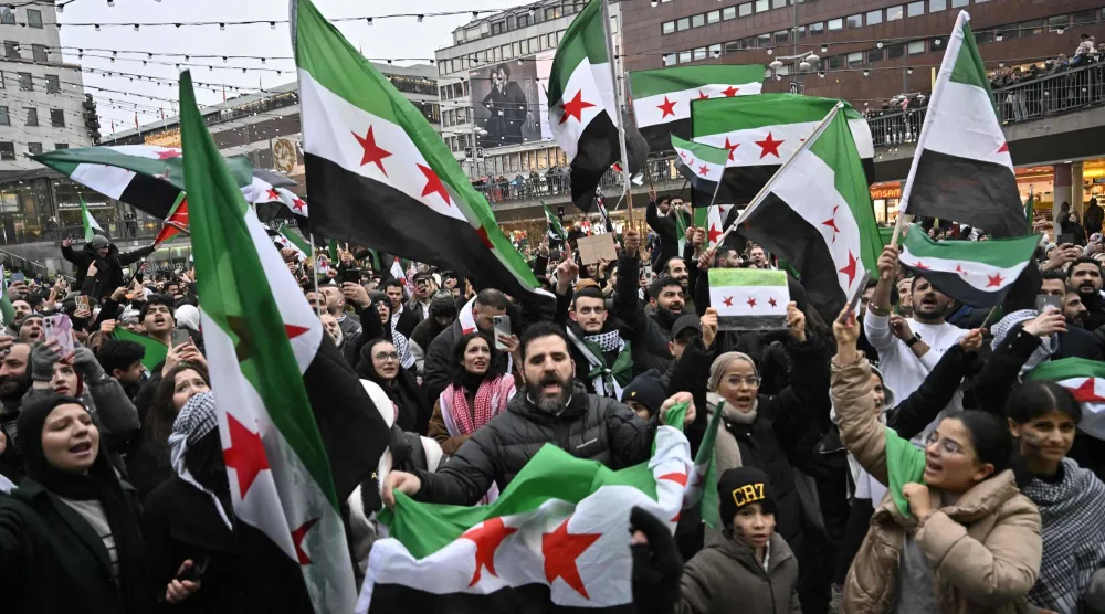أفراد من الجالية السورية بالسويد يحملون الأعلام السورية أثناء تجمعهم في 8 ديسمبر 2024 في ساحة سيرغيل في استوكهولم للاحتفال بنهاية حكم نظام الأسد (أرشيفية - أ.ف.ب)