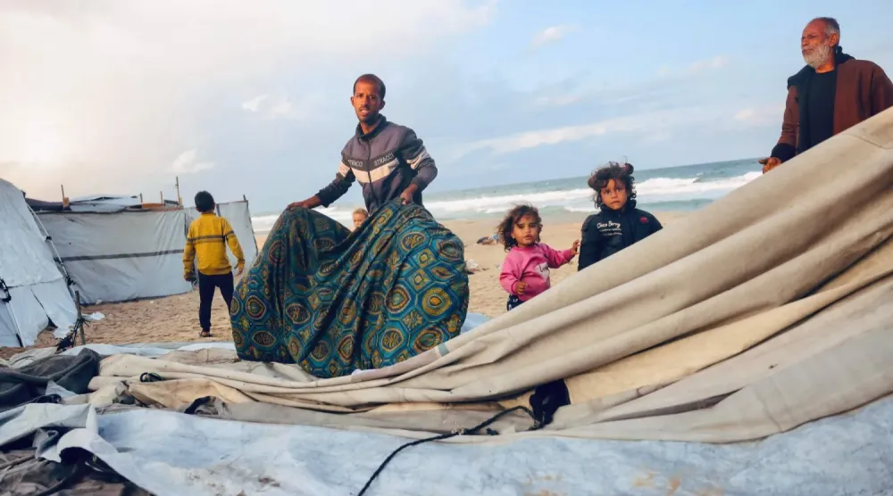 Gazze Şeridi'nin merkezindeki Deyr el-Belah'ta yerinden edilmiş Filistinliler için kurulan geçici kampta zor şartlarda yaşıyorlar (AFP)