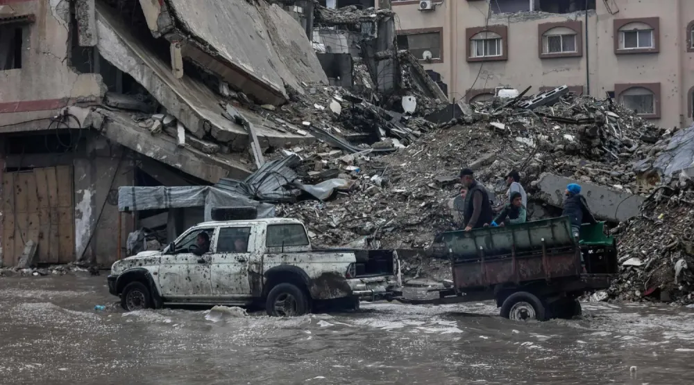 Dün şiddetli yağmurların ardından Gazze şehrindeki bir mülteci kampında, bir araba tarafından çekilen römorkta bulunan Filistinliler (AFP)