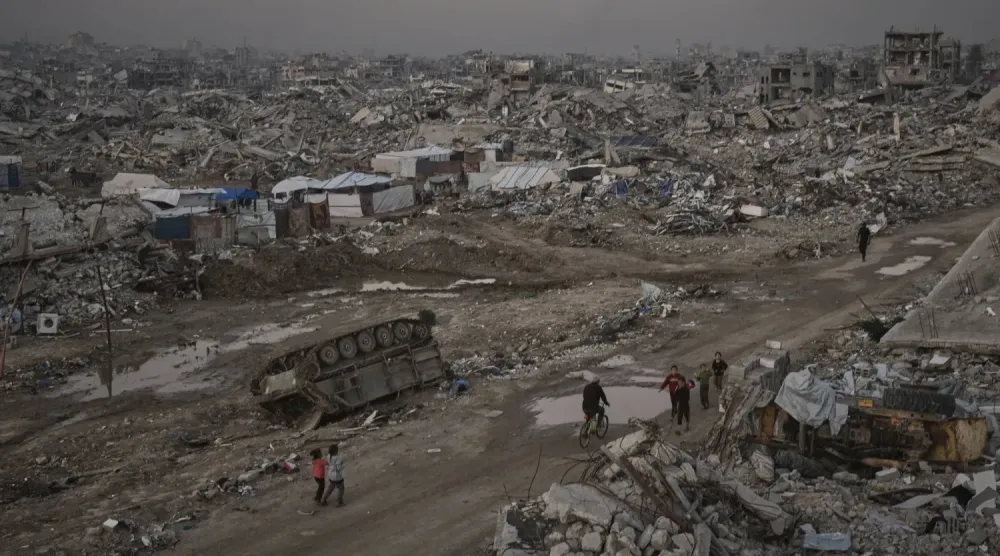 Filistinliler, perşembe günü Gazze Şehri'nde tahrip edilmiş bir İsrail askeri aracının yanından geçiyorlar (AP)