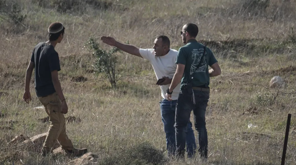 فلسطيني من سكان قرية ترقوميا بالضفة الغربية يتجادل مع مستوطنين إسرائيليين خلال احتجاج على مصادرةٍ للأراضي في المنطقة (أسوشييتد برس)