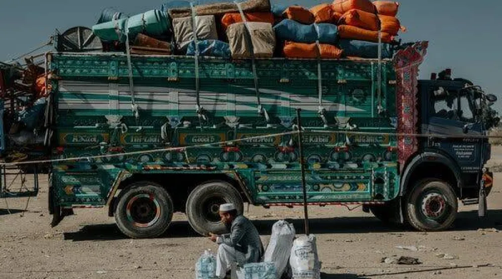 لاجئ أفغاني تم ترحيله ينتظر هذا الشهر بجوار شاحنات ركاب متوقفة بالقرب من معبر تورخام الحدودي في باكستان (نيويورك تايمز » 