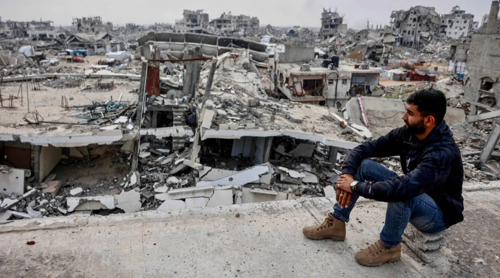 نازح يطل من مبنى متضرر على الدمار في حي تل الهوى بمدينة غزة يوم السبت (أ.ف.ب)