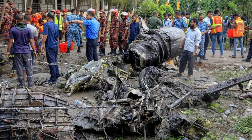 21 Temmuz 2025'te Dakka'da meydana gelen uçak kazasının yaşandığı yerde itfaiye ve güvenlik personeli çalışıyor (AFP)