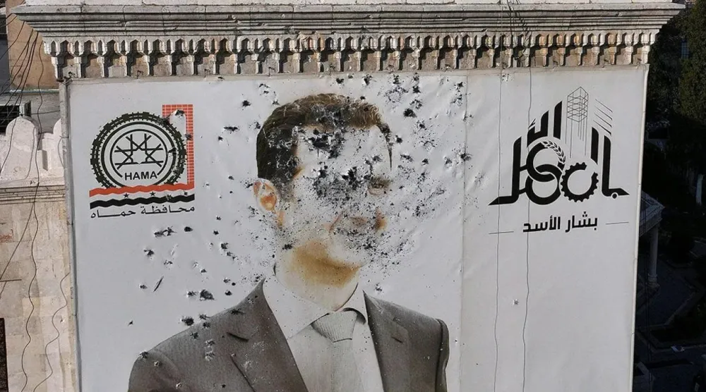 HTŞ öncülüğündeki isyancılar, Suriye'yi ele geçirirken Esad'ın posterlerini parçalamıştı (AFP)