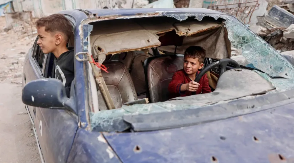 Gazze'nin Tel el-Heva mahallesindeki iki Filistinli çocuk, hasar görmüş bir arabada oynuyor. (AFP)