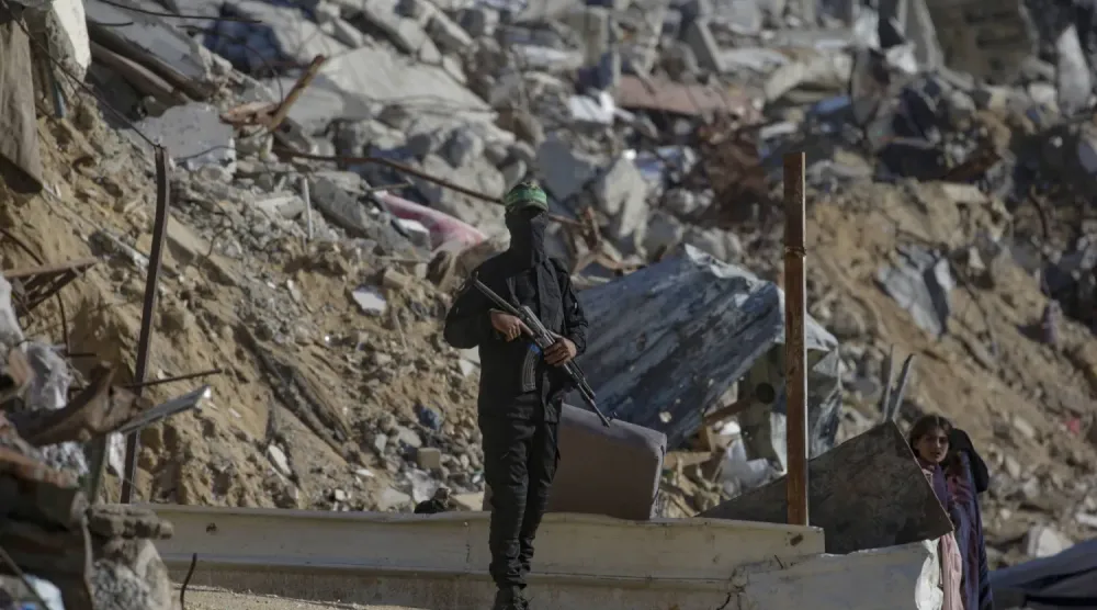 Hamas'ın askeri kanadı İzzeddin el-Kassam Tugayları’na mensup bir savaşçı, Uluslararası Kızılhaç Komitesi (ICRC) personeli ve Hamas mensupları Gazze Şeridi'nin kuzeyindeki Cibaliye Mülteci Kampı’nda İsrailli rehinelerin cesetlerini ararken alanda nöbet tutuyor. (EPA)