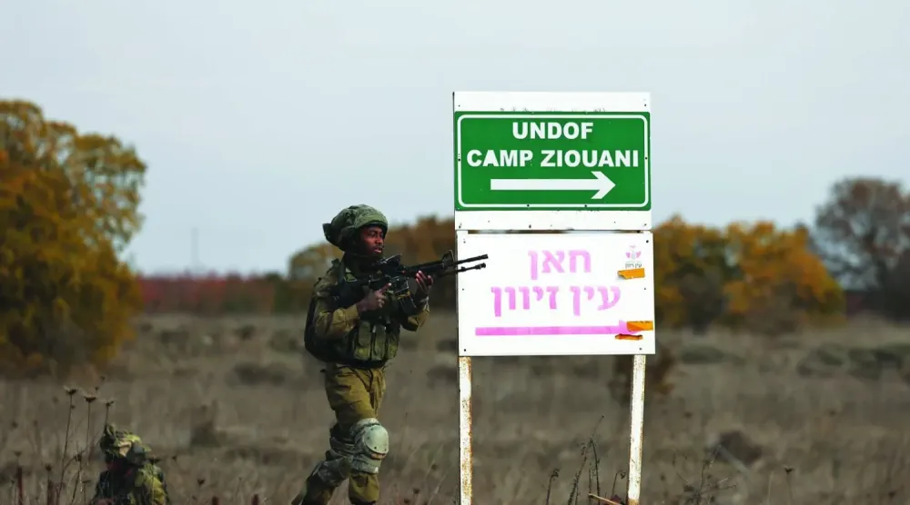 Golan Tepeleri'nde bulunan Kuneytra geçiş noktası yakınlarındaki Birleşmiş Milletler Ateşkes Gözlem Gücü (UNDOF) karakolunda bir tabelanın yanında duran iki İsrail askeri. (EPA)