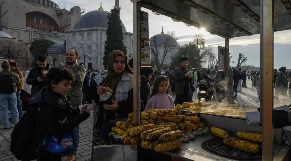 أم وأولادها يشترون الذرة من بائع متجول في إسطنبول (أ.ف.ب)