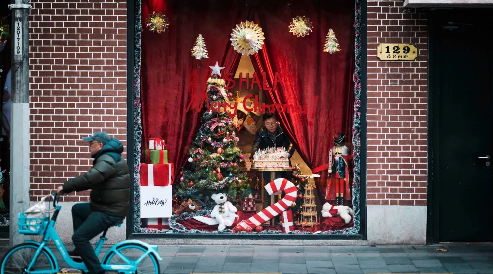 رجل ينسق واجهة أحد المتاجر في مدينة شنغهاي الصينية بمناسبة أعياد رأس السنة (إ.ب.أ)