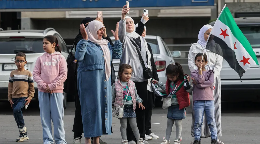  سوريون يتابعون من جانب الطريق سيارات وزارة الداخلية خلال الإطلاق الرسمي لهويتها البصرية الجديدة في دمشق (أ.ب)