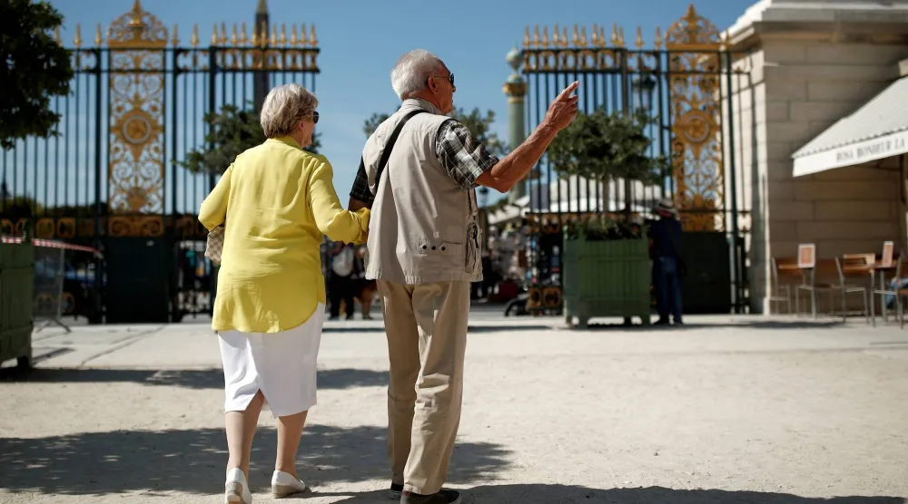 مسنان يتجولان داخل حديقة في باريس (رويترز)