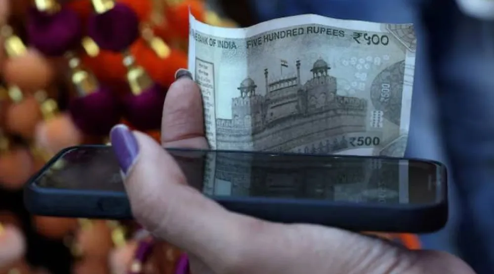 امرأة تمسك بورقة نقدية فئة 500 روبية في الأحياء القديمة لدلهي (رويترز)