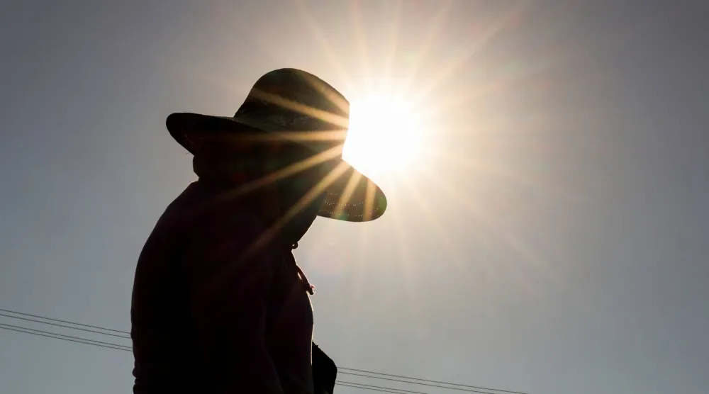 عامل يقف تحت أشعة الشمس وسط درجات الحرارة المرتفعة (رويترز)