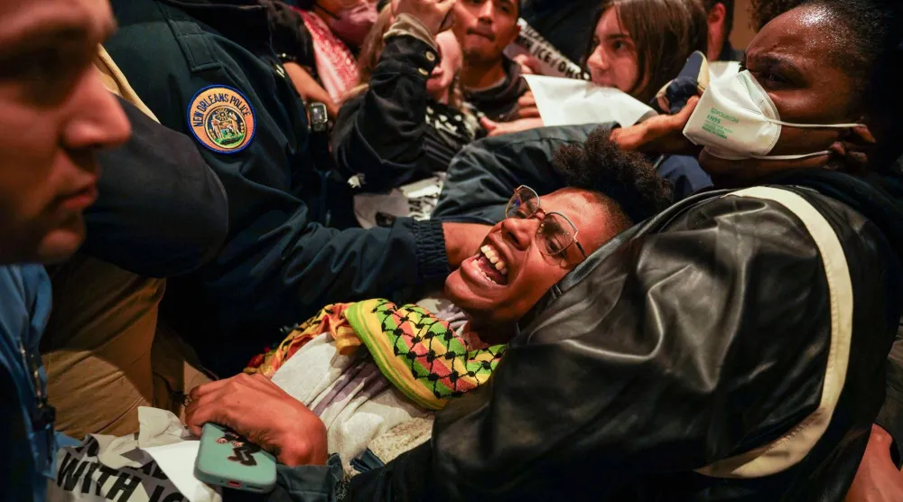 ضباط شرطة نيو أورلينز يحملون رجلاً خارج مبنى البلدية بعد مشاركته في احتجاج على نشر عملاء فيدراليين في المدينة (أ.ف.ب)