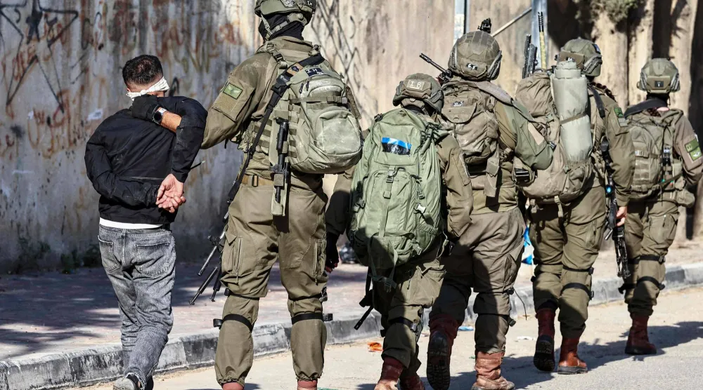 جنود إسرائيليون يعتقلون فلسطينياً خلال عملية عسكرية في قلقيلة بالضفة الغربية الخميس (د.ب.أ)