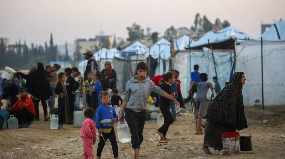 يملأ فلسطينيون حاوياتهم بالمياه في مخيم النصيرات للنازحين الفلسطينيين وسط قطاع غزة (أ.ف.ب)