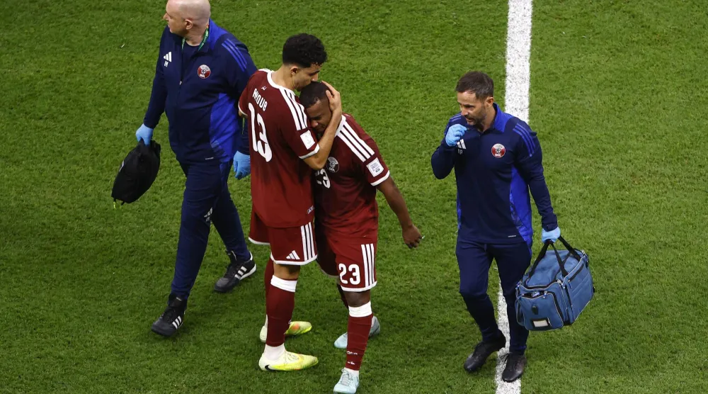 لاعب المنتخب القطري عاصم ماديبو لدى خروجه من الملعب مصاباً في مواجهة فلسطين (رويترز)
