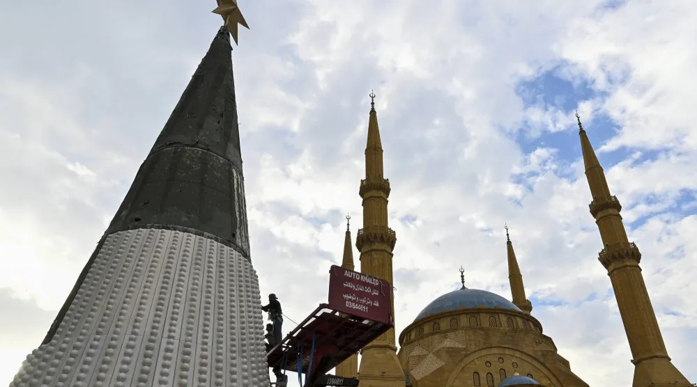 عمال يستخدمون رافعة لتعليق زينة شجرة عيد الميلاد المقامة أمام مسجد محمد الأمين في وسط بيروت (إ.ب.أ)