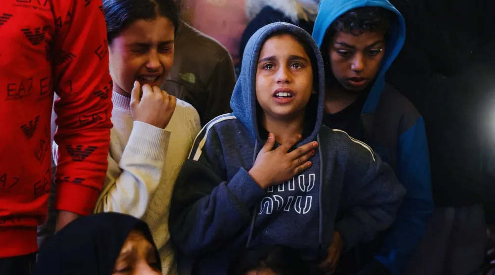 أطفال فلسطينيون يبكون خلال حضور جنازة أشخاص قُتلوا في خان يونس (أ.ف.ب)