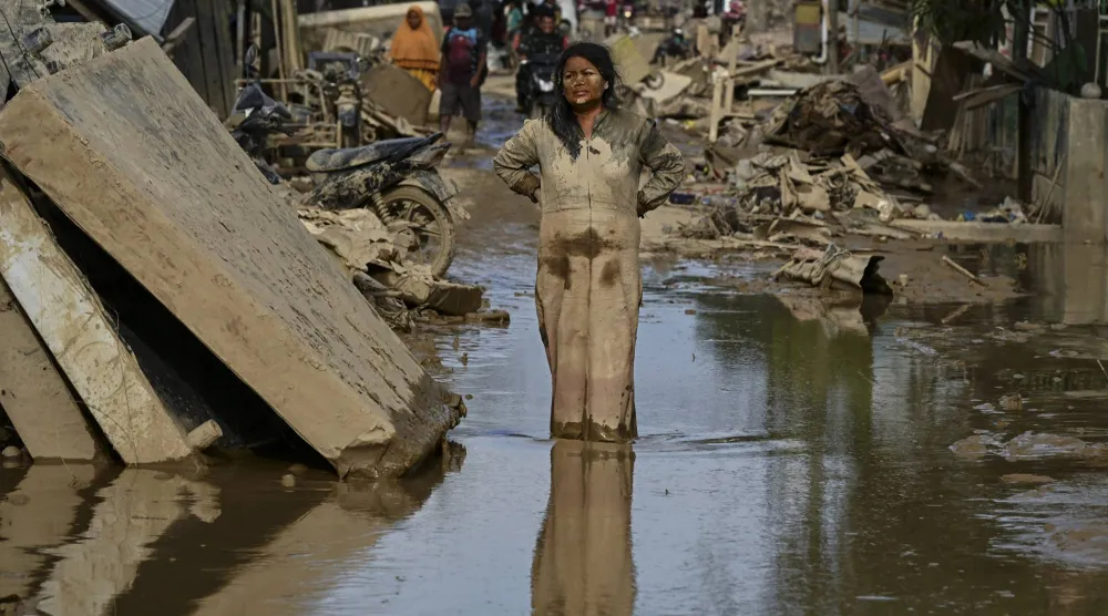 سيدة إندونيسية مغطاة بالطمي بعدما أغرقت الفيضانات إقليم آتشيه تاميانغ الإندونيسي (أ.ف.ب)