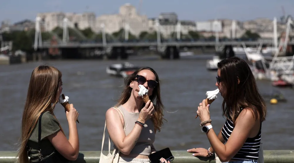 فتيات يتناولن الآيس كريم على جسر ويستمنستر في لندن (إ.ب.أ)