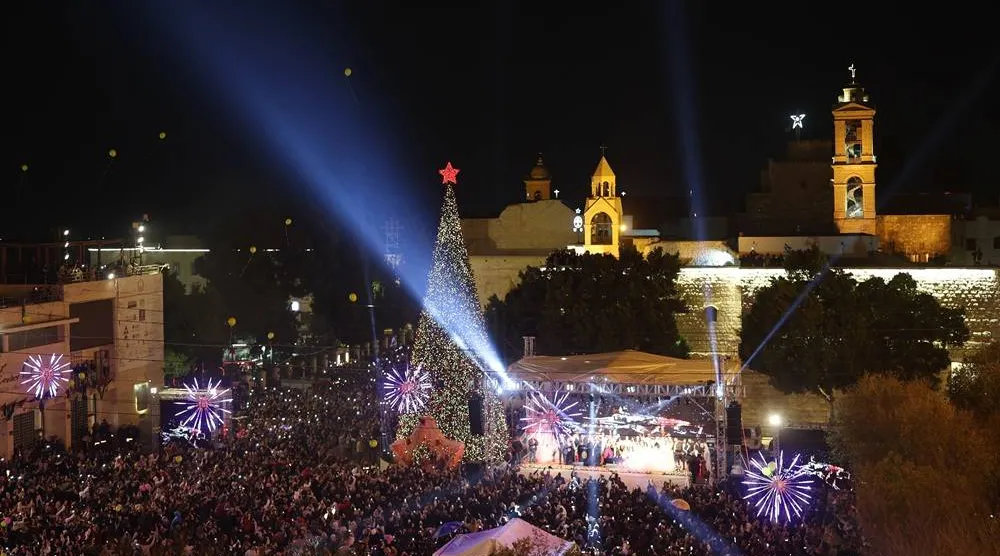People gather during the lighting of the Christmas tree ceremony at the Manger Square, next to the Church of Nativity in the background, in the West Bank city of Bethlehem, 06 December 2025. (EPA)