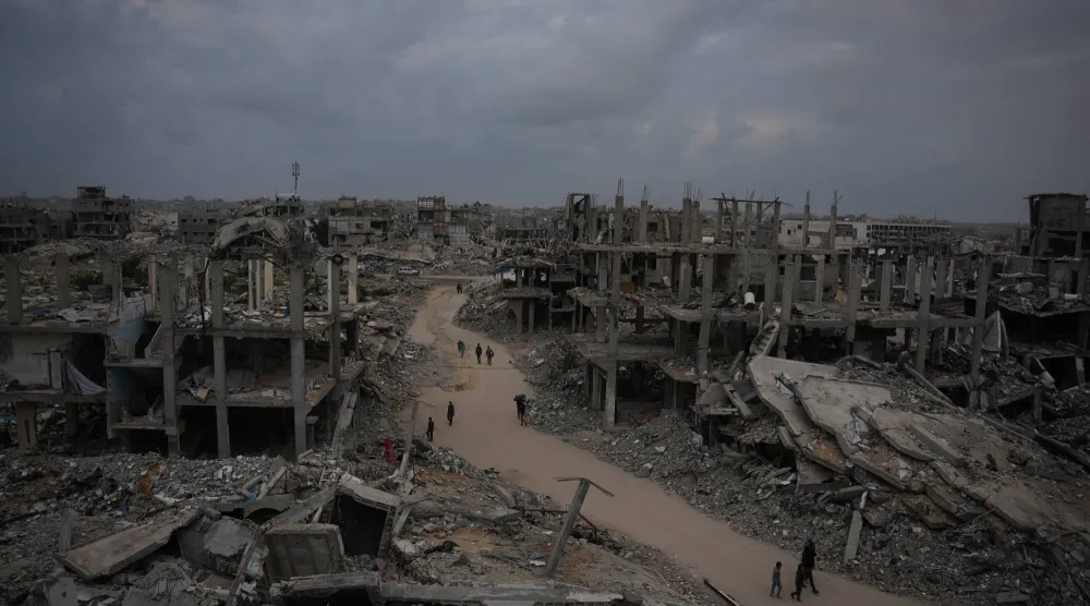 فلسطينيون يسيرون في أحد شوارع جباليا شمال قطاع غزة وسط مبانٍ دمَّرتها الحرب الإسرئيلية على القطاع (أ.ب)