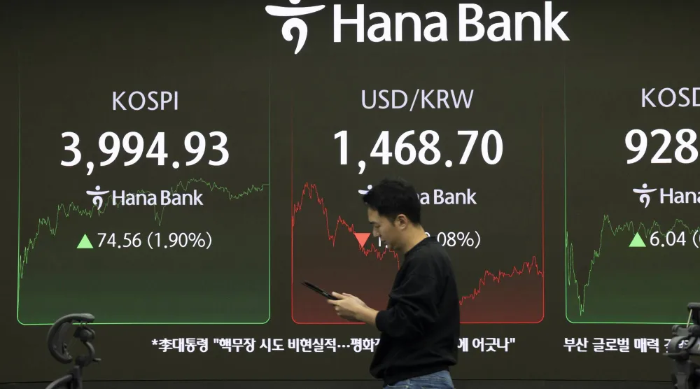 متداول يمر أمام شاشات تعرض مؤشر «كوسبي» ببنك هانا في سيول (إ.ب.أ)
