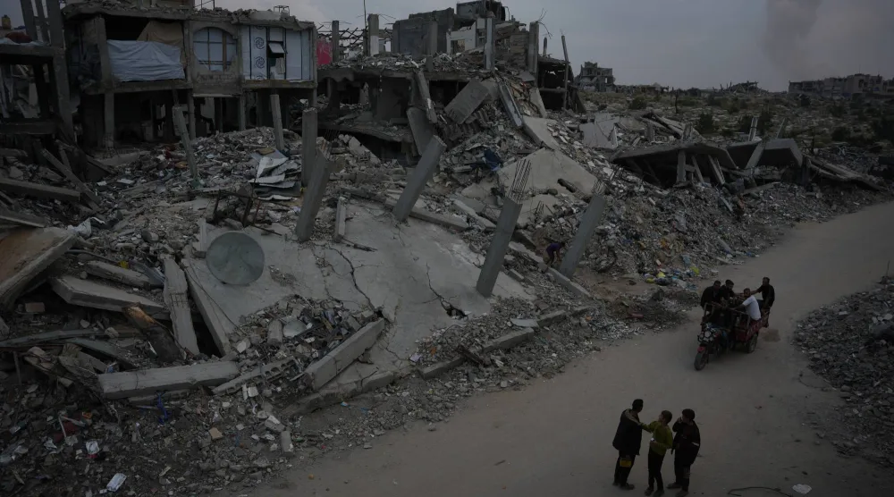 فلسطينيون يقفون يوم السبت أمام الأنقاض في جباليا بشمال قطاع غزة (أ.ب)