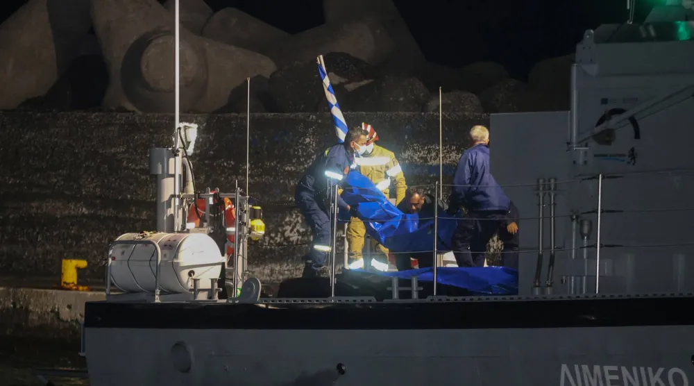 عناصر خفر السواحل في اليونان يحملون أكياساً تضم جثث مهاجرين غرقى (رويترز)