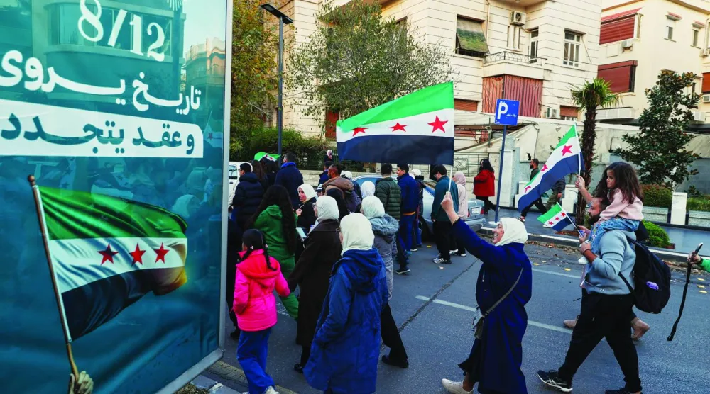 
سوريون يلوحون بأعلام بلدهم وهم يشاركون في الاحتفالات بسقوط نظام بشار الأسد في دمشق أمس (أ.ب)