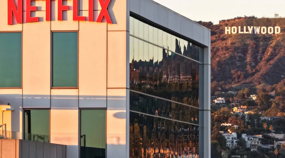 شعار «نتفليكس» معروض في استوديوهاتها مع لافتة هوليوود في الأفق (أ.ف.ب)