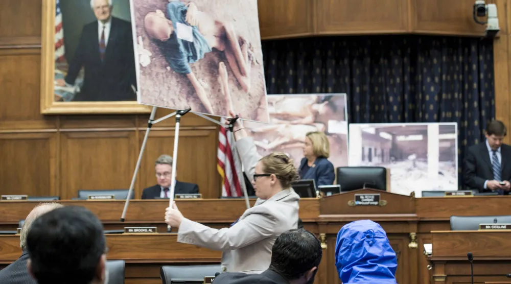 صورة أرشيفية لـ«قيصر» مخفياً هويته بمعطف أزرق خلال جلسة نقاش في الكونغرس الأميركي لقانون حماية المدنيين السوريين (أ.ف.ب)