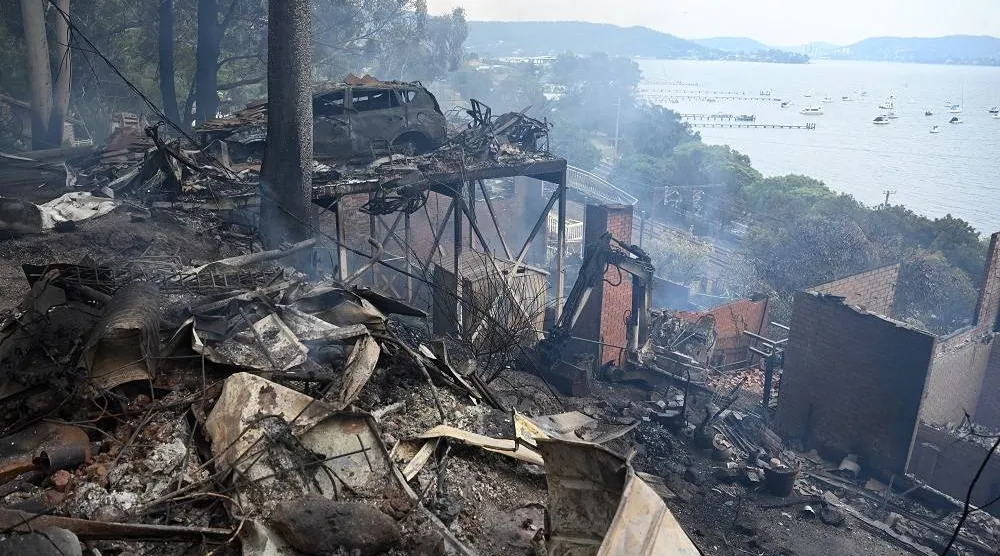 Ruins of buildings and a car smolder after a wildfire destroyed houses in Koolewong, Australia, Saturday, Dec. 6, 2025. (Dan Himbrechts/AAP Image via AP)