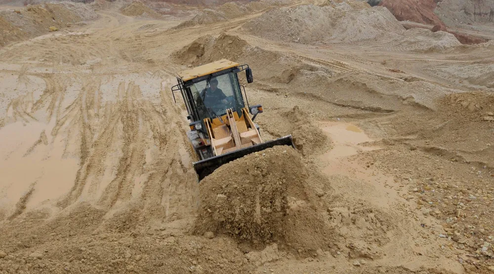 عامل يقوم برفع الرمال في موقع للمعادن النادرة في إقليم جيانغتشي الصيني (رويترز)