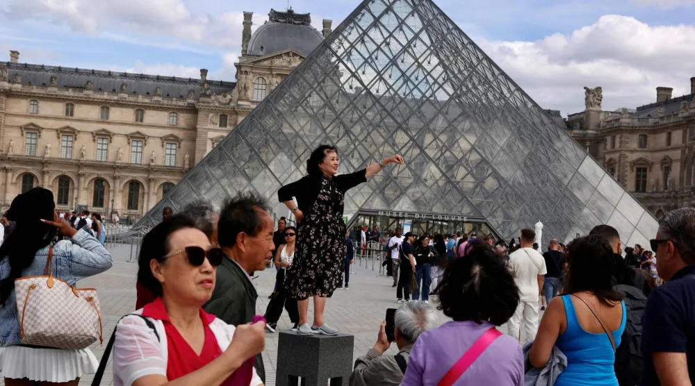 سياح بـ«اللوفر» يلتقطون صوراً أمام المتحف في باريس (رويترز)