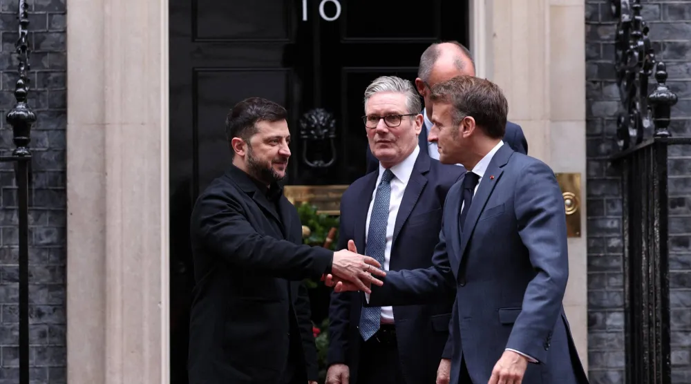 زيلينسكي يصافح الرئيس الفرنسي إيمانويل ماكرون بعد اجتماع مع رئيس الوزراء البريطاني كير ستارمر والمستشار الألماني فريدريش ميرتس في لندن الاثنين (رويترز)