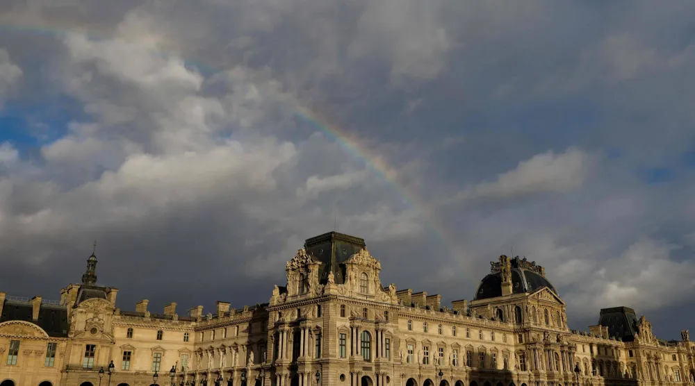 A rainbow emerges over the Louvre museum, bathed in late afternoon sunlight, in Paris, on December 6, 2025. (AFP)