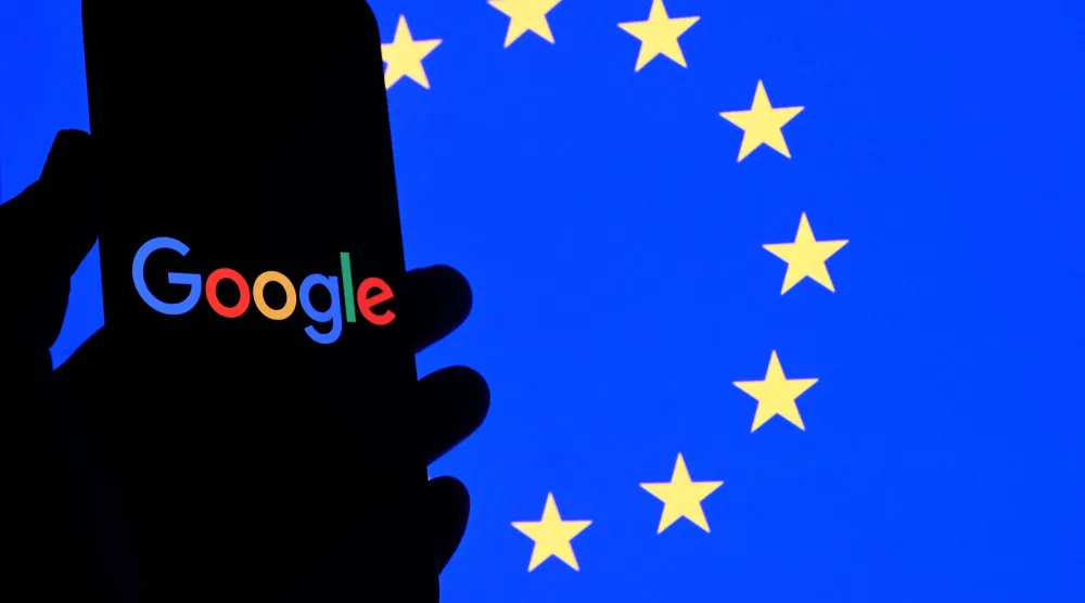 شعار «غوغل» على هاتف ذكي أمام علم الاتحاد الأوروبي في بروكسل (أ.ف.ب)
