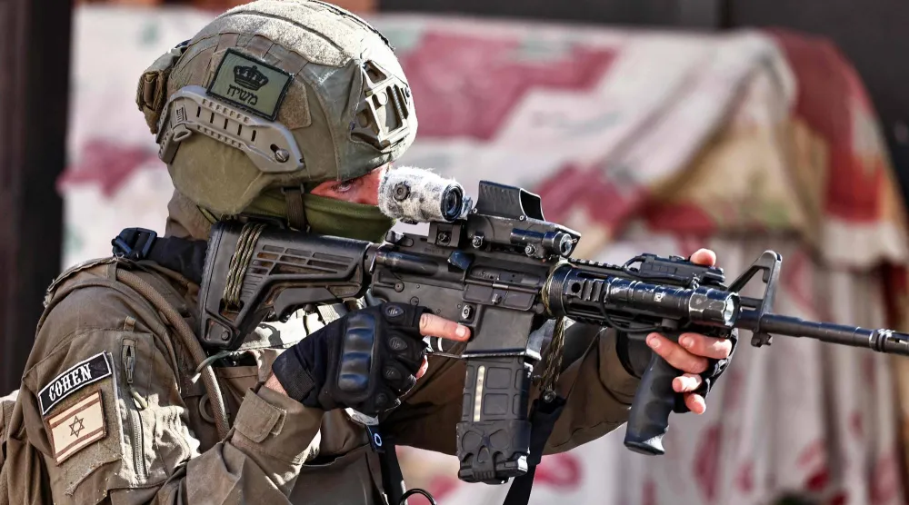 جندي إسرائيلي يوجِّه سلاحه خلال عملية عسكرية في بلدة قلقيلية بالضفة الغربية (أ.ف.ب)